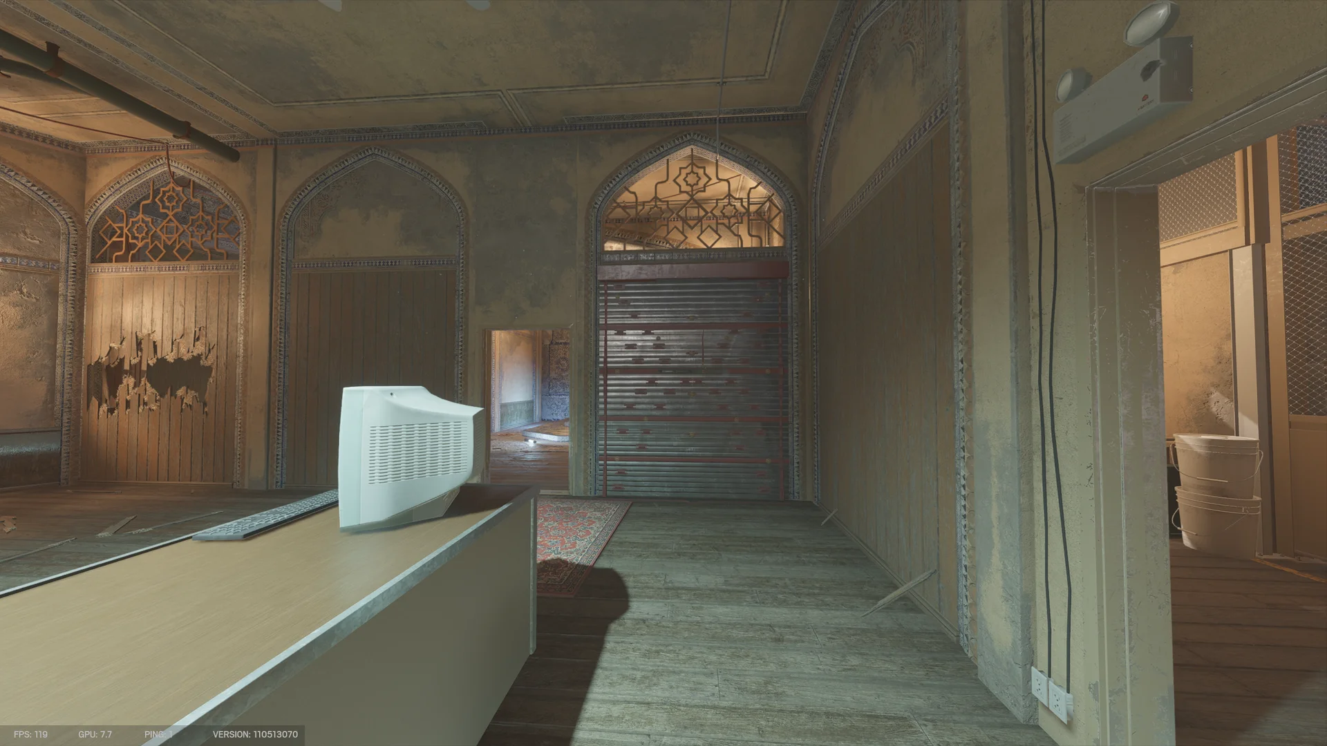 Arched room on Border 1F with a CRT monitor and keyboard on a long counter, a closed metal shutter in an archway, and torn wooden paneling at left