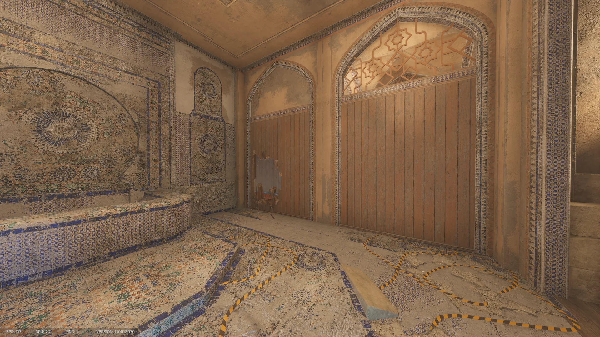 Mosaic-tiled room on Border 1F with a curved raised basin, arched wooden partitions, a small breach low in one panel, and hazard tape on the floor