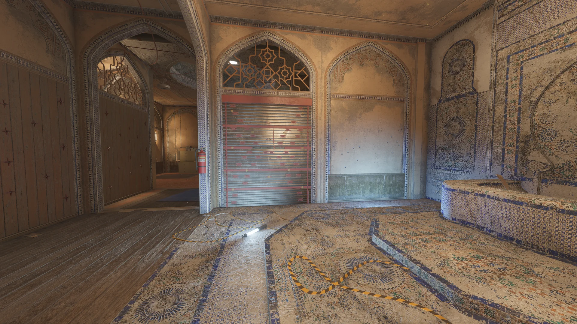 Ornate arched hall on Border 2F with a closed red-framed metal shutter, a fire extinguisher, mosaic flooring with hazard tape, and a tiled platform at right