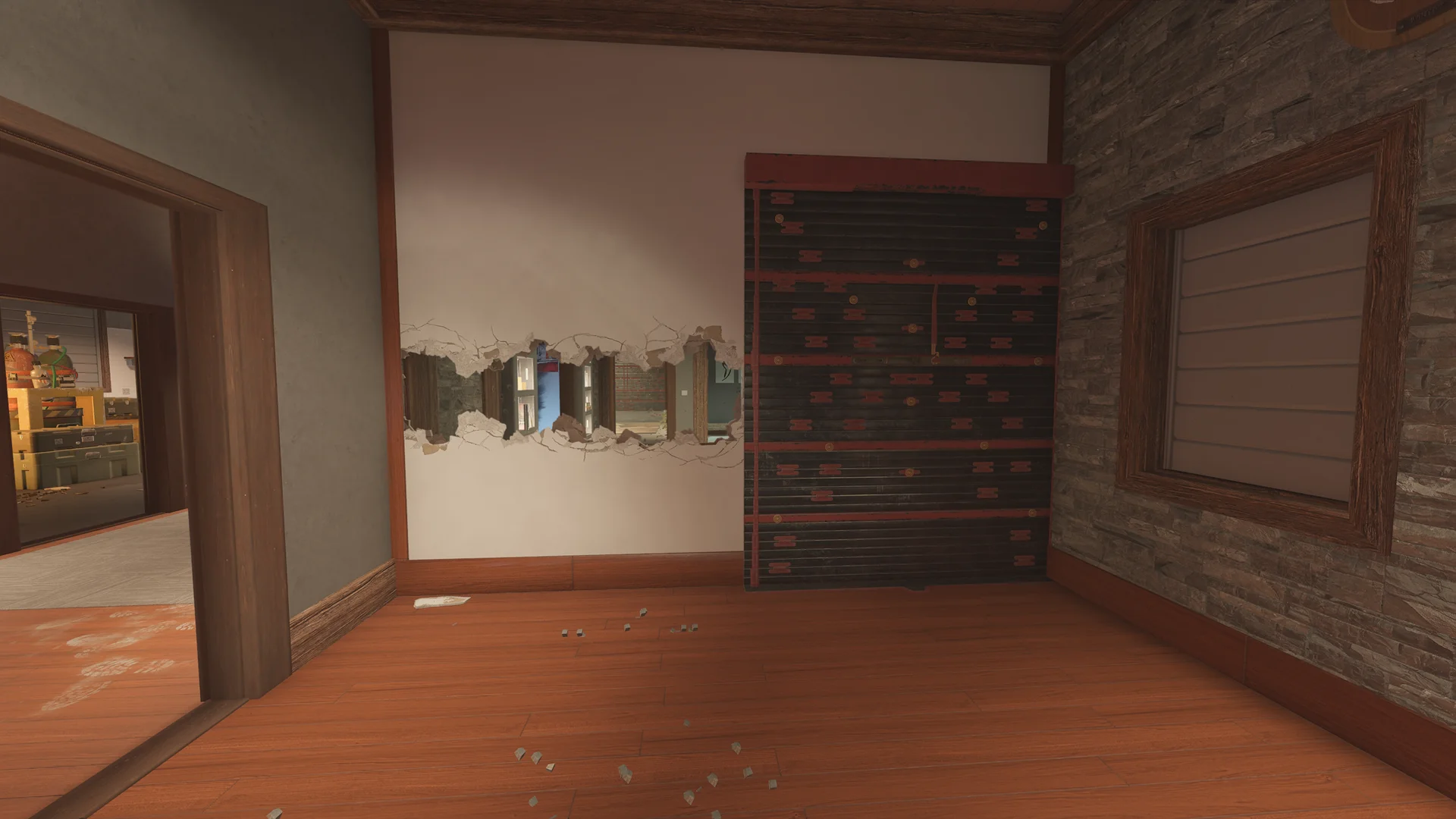 Room on Chalet 1F with a long jagged breach in the wall, a reinforced panel at right and a storeroom seen through the door