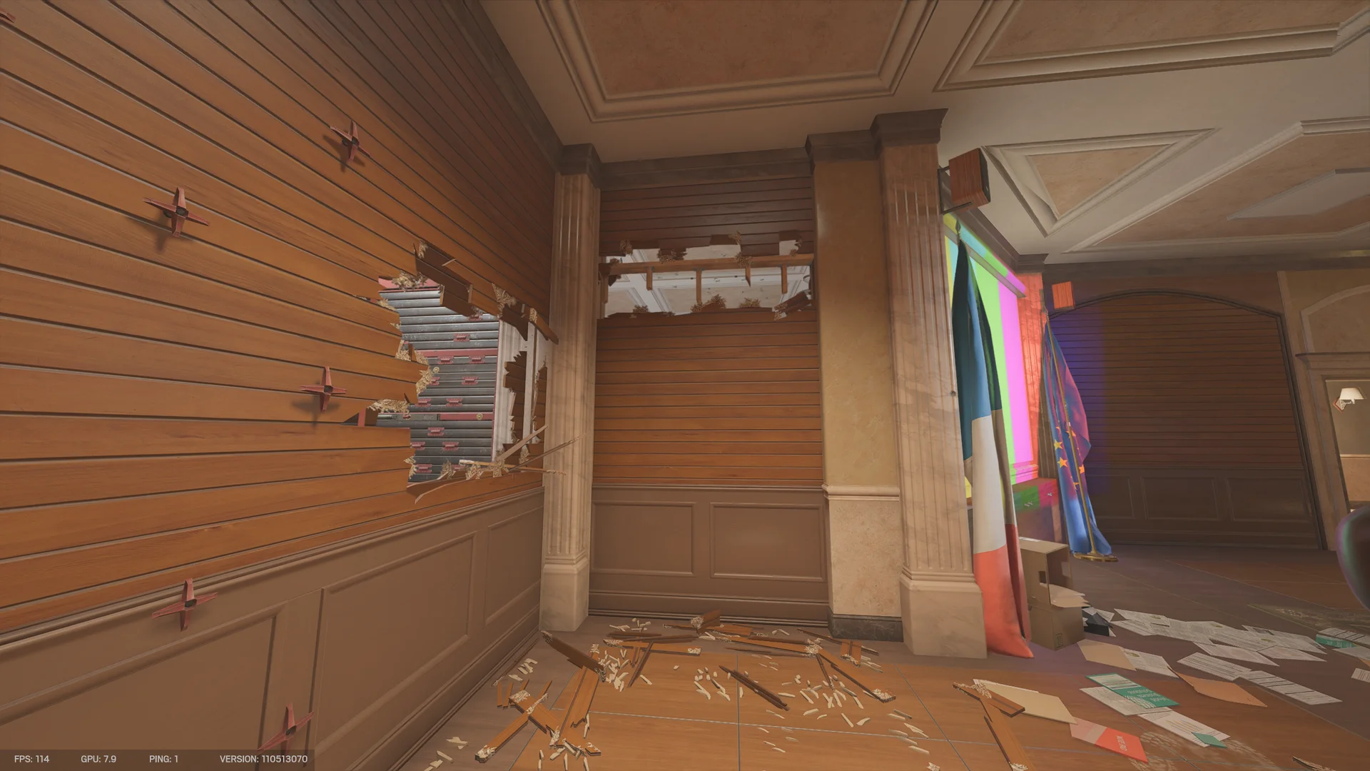 Wood-panelled hall on Consulate 2F with red cross markers on the wall, a breach hole to a reinforced shutter, flags, and wood debris
