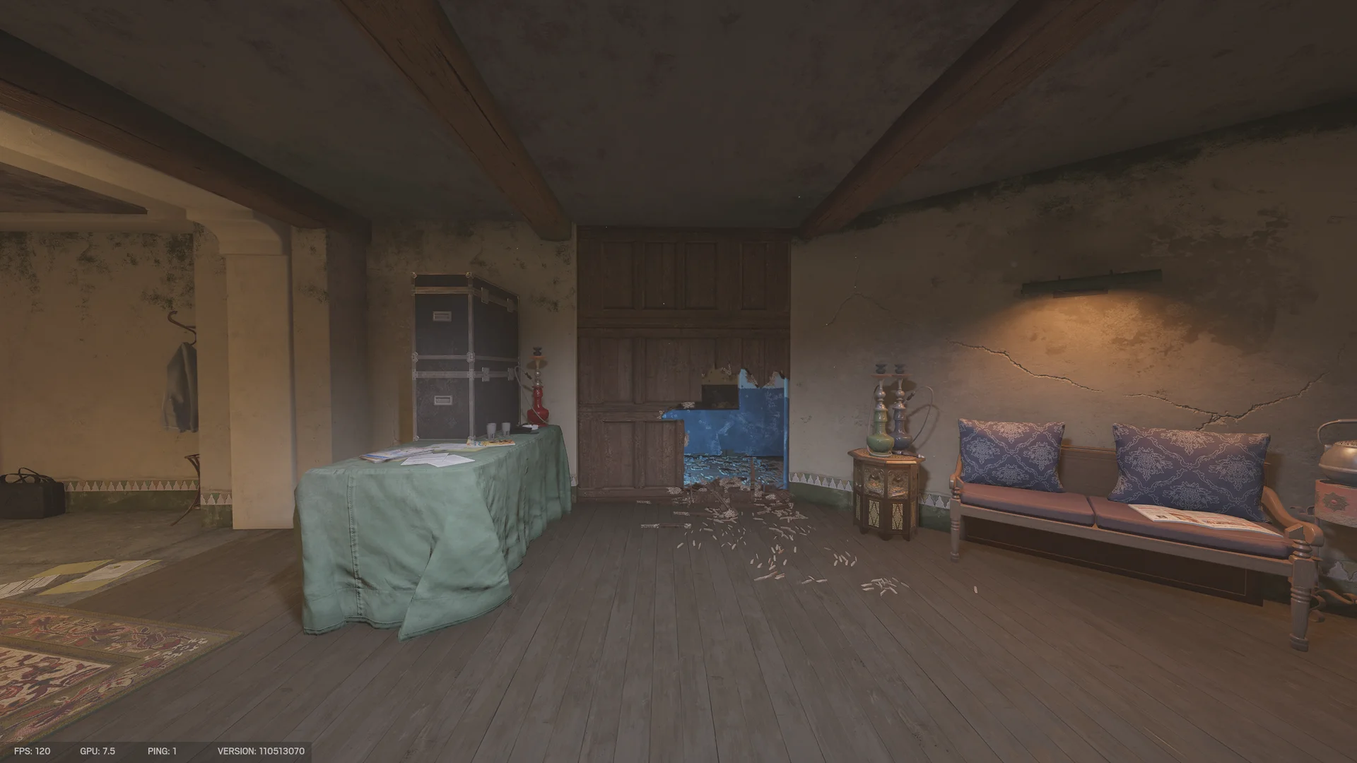 Lounge on Fortress with a cloth-draped table holding a hookah, a road case trunk, a breach hole through a wood-panel wall, and a bench