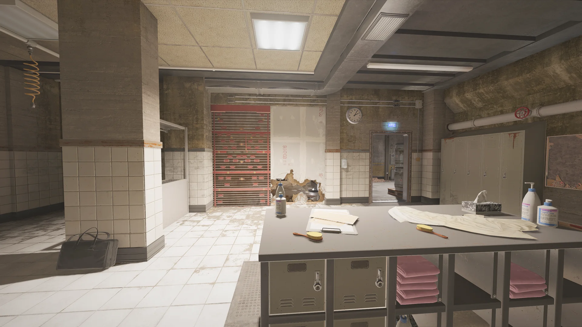 Locker room in the Lair basement with white-tiled walls, a reinforced shutter, a wall clock, grey lockers, and a counter with folded towels