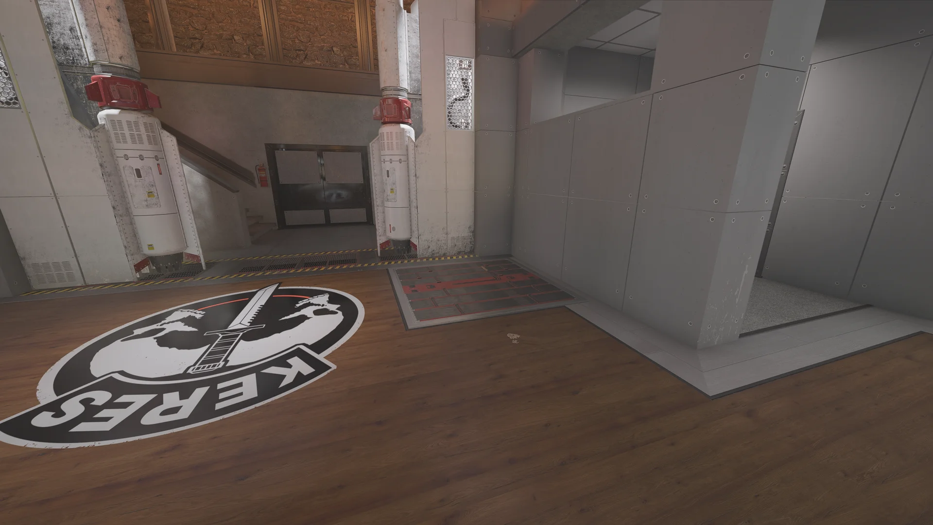 Atrium in the Lair basement with metal-panel walls, two wall-mounted cylinders, a floor logo, a reinforced floor hatch, and a stairwell