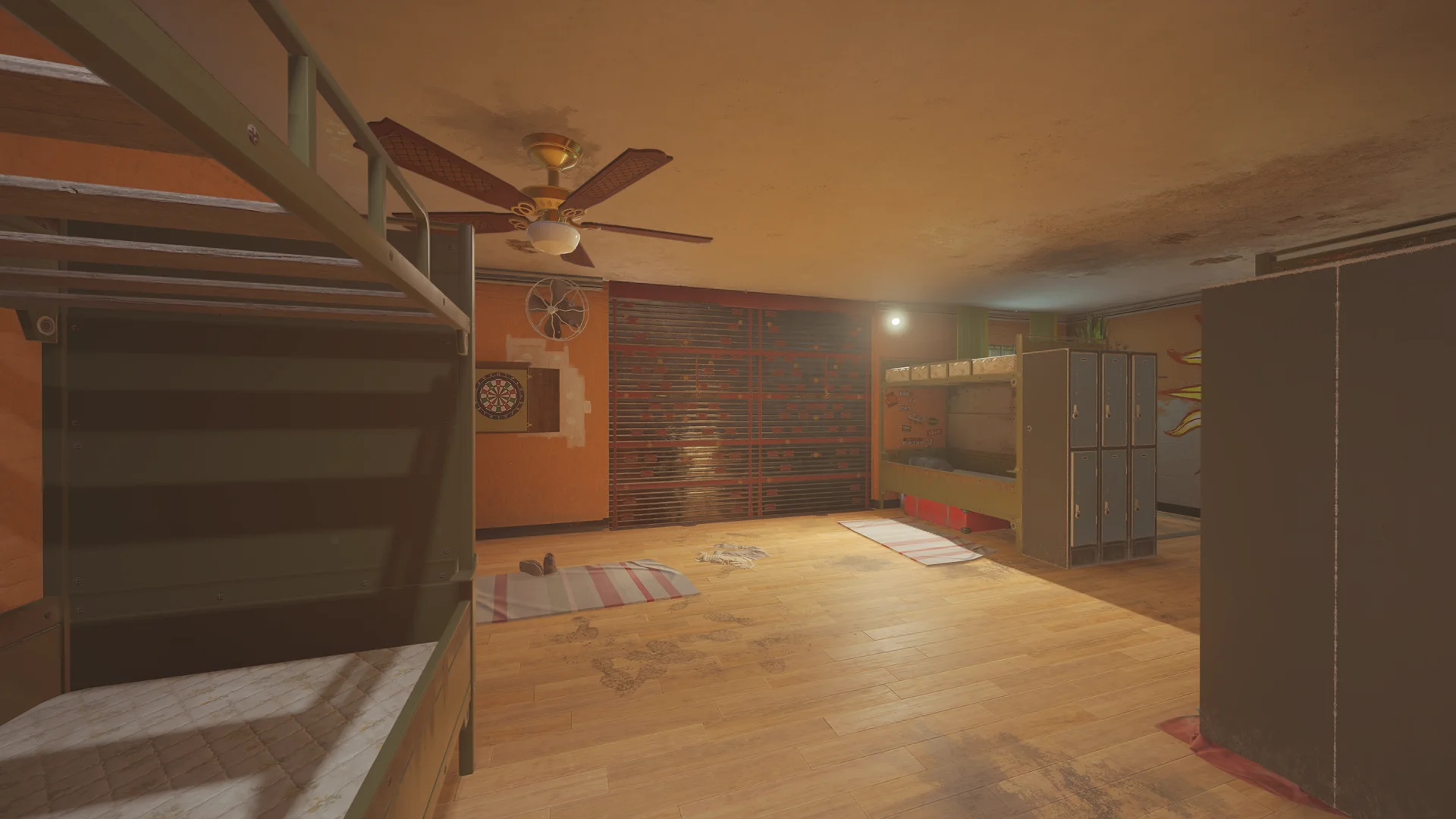 Dorm on Outback with metal bunk beds, a dartboard, a ceiling fan, lockers and two reinforced shutters along the wall