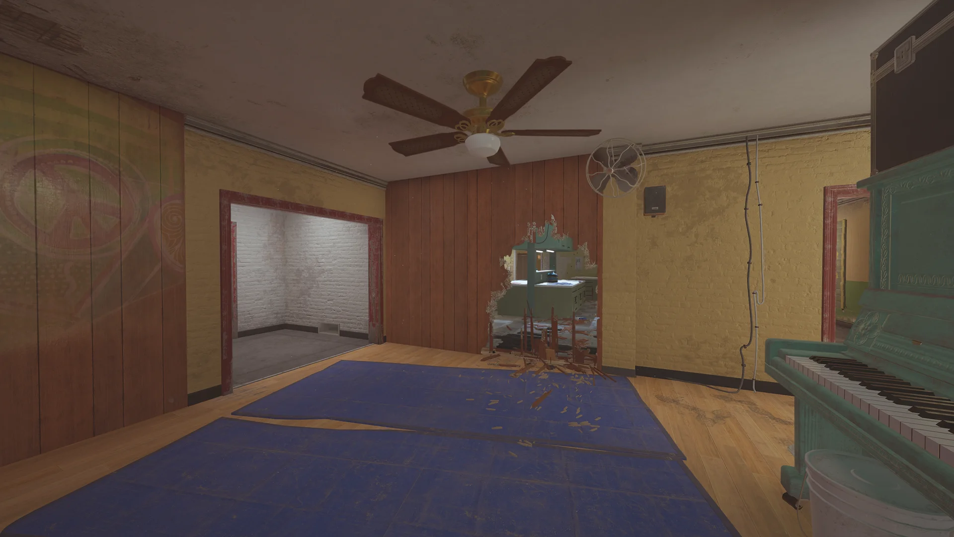 Room on Outback 1F with a teal upright piano, blue floor mats, a ceiling fan and a breach hole opening to a kitchen