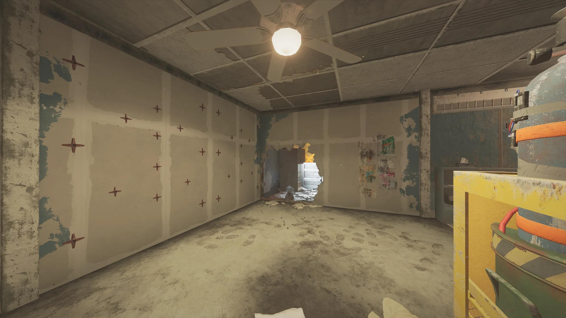 Stripped room on Theme Park 2F with rebar-marked drywall, a hole broken low through a wall, a ceiling fan, and boot prints
