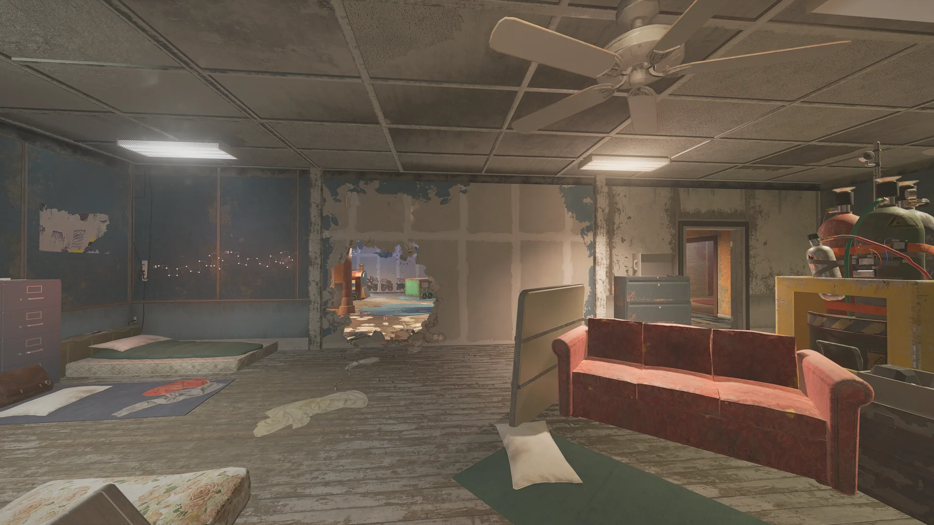 Run-down room on Theme Park 2F with floor mattresses, a red couch, gas cylinders, and a large hole broken through the drywall